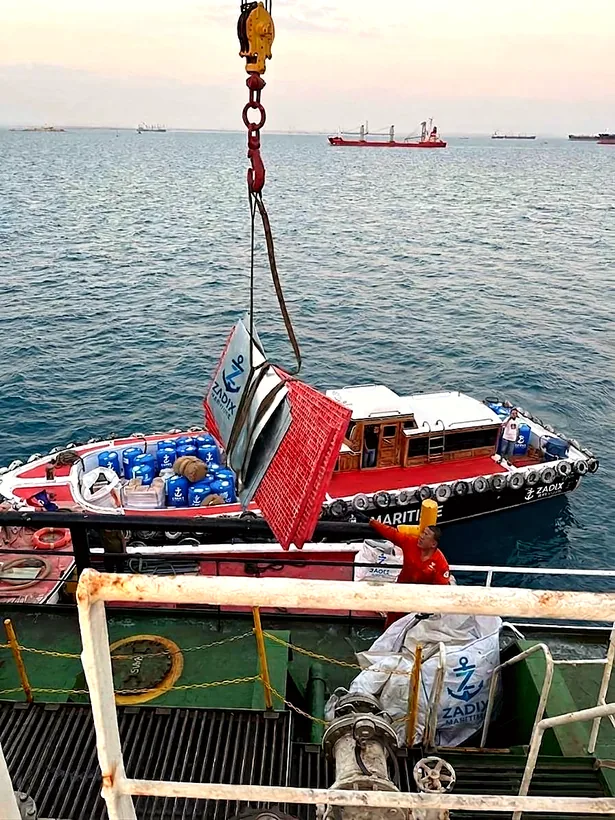 Ship crane lifting supplies from a Zadix launch at sea