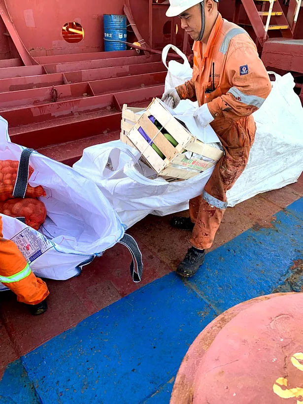 Ship crew receiving crates of fresh provisions on deck